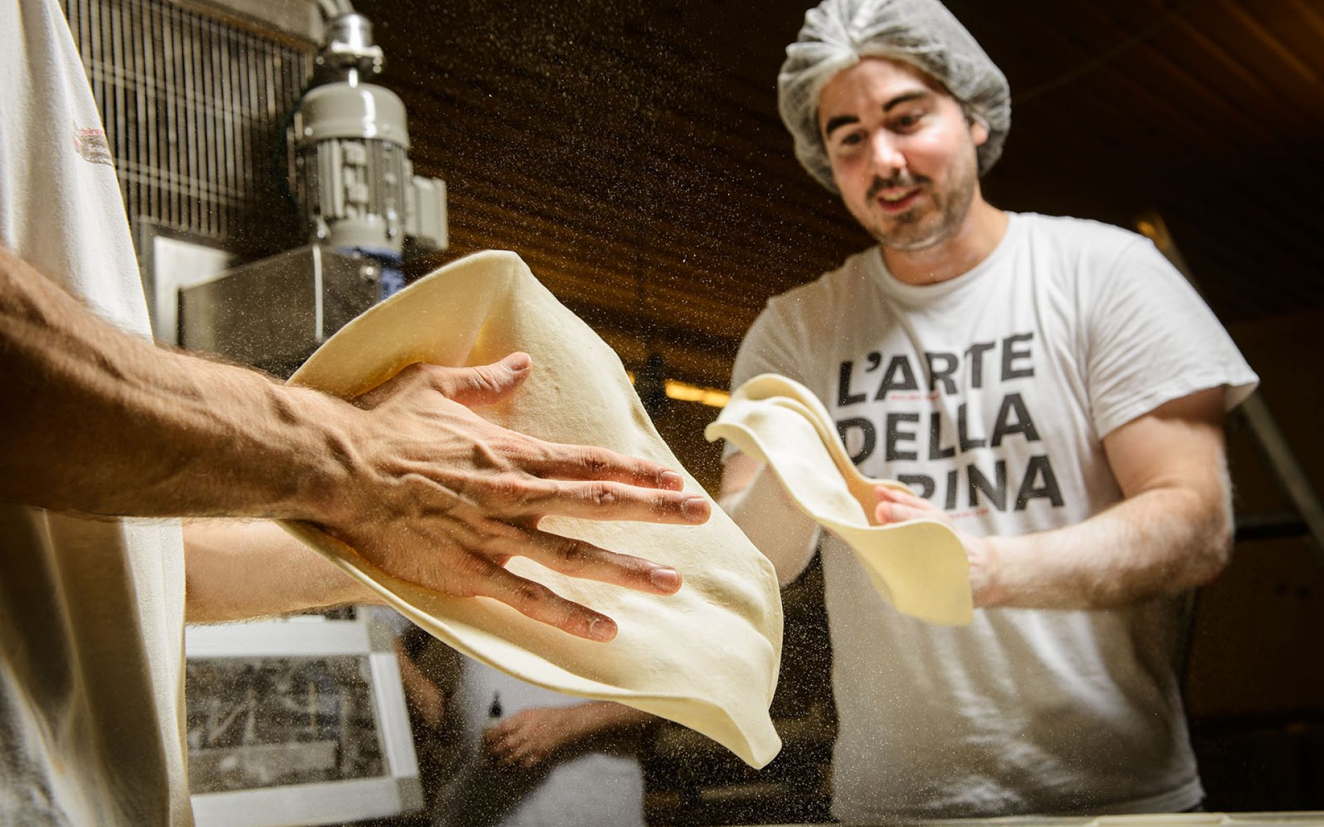 Pizzabäcker wirft Pizzateig durch die Luft
